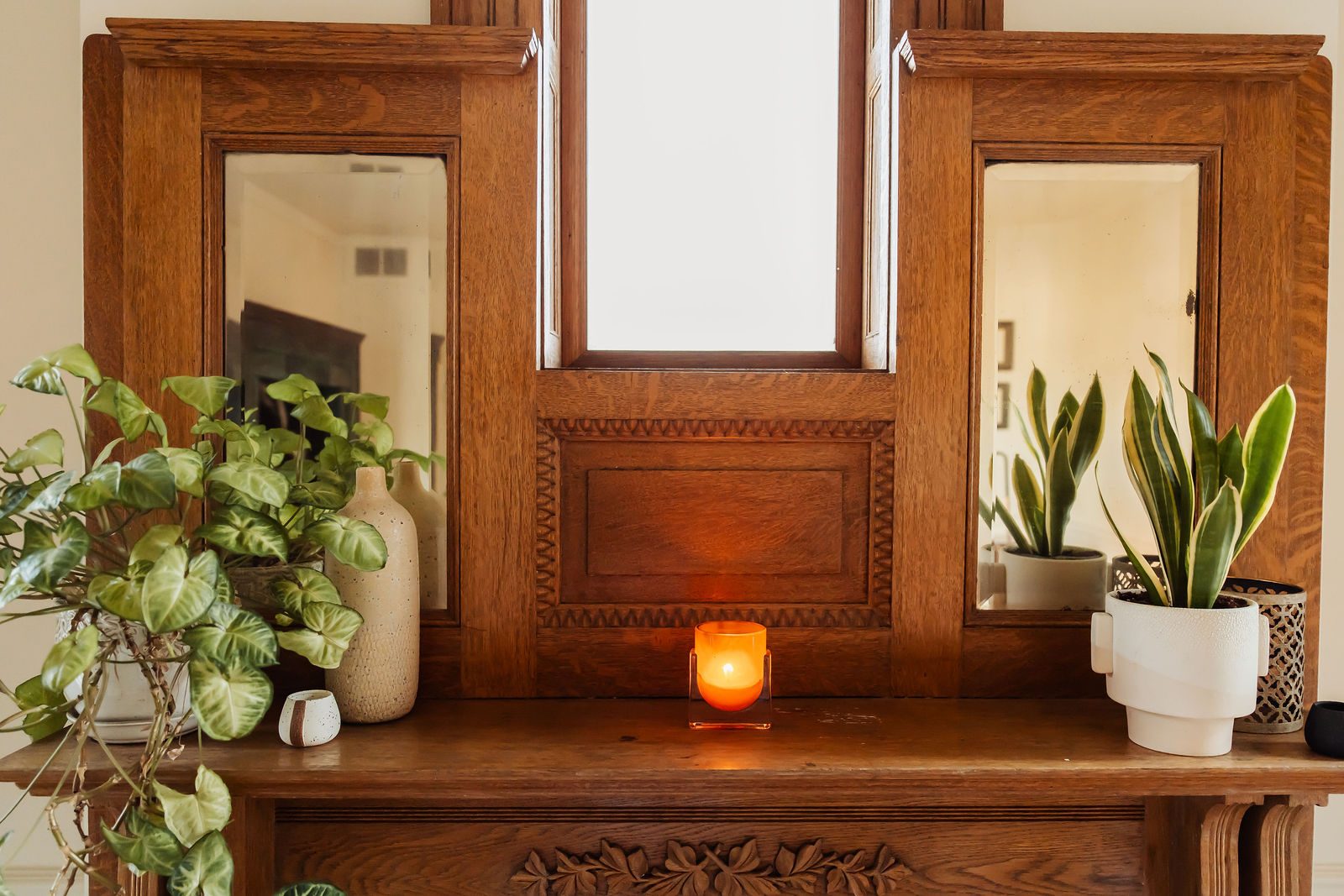 A candle and potted plants on the carved oak mantel in Dr. Rosen's office