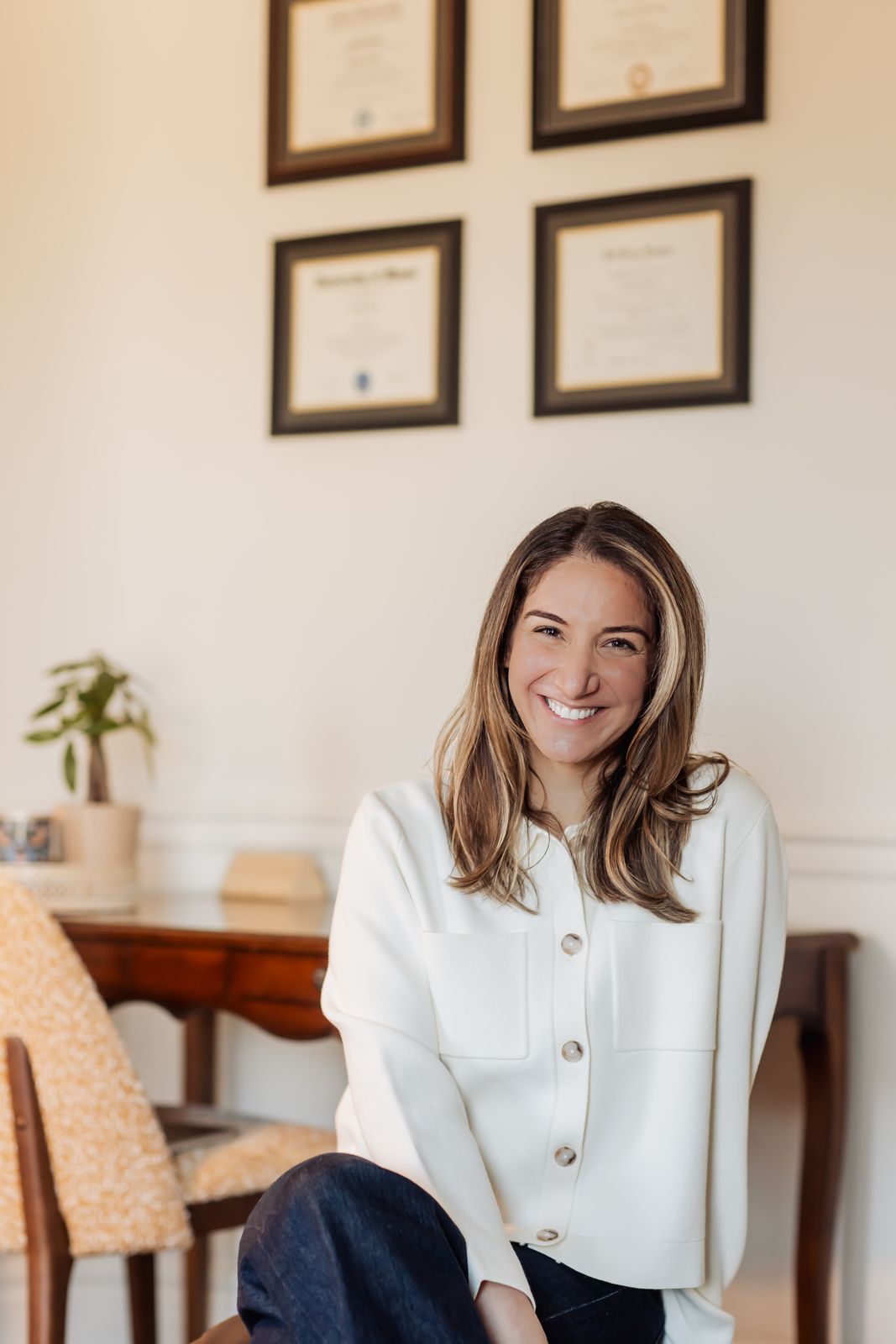Dr. Lindsay Rosen laughing in her Denver office, with her framed diplomas on the wall behind her