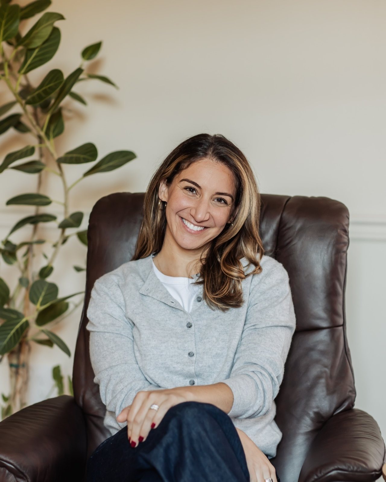 Dr. Lindsay Rosen smiling in the leather chair in her Denver office, beside a fig tree